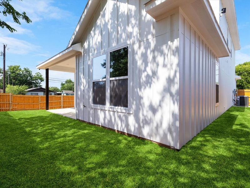 Spacious grassy yard featuring a concrete patio and a covered outdoor area with a dark support column Spacious grassy yard featuring a concrete patio and a covered outdoor area with a dark support column
