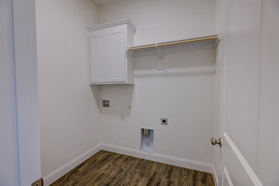 Clothes washing area featuring hookup for a gas dryer, dark wood-type flooring, hookup for an electric dryer, hookup for a washing machine, and baseboards