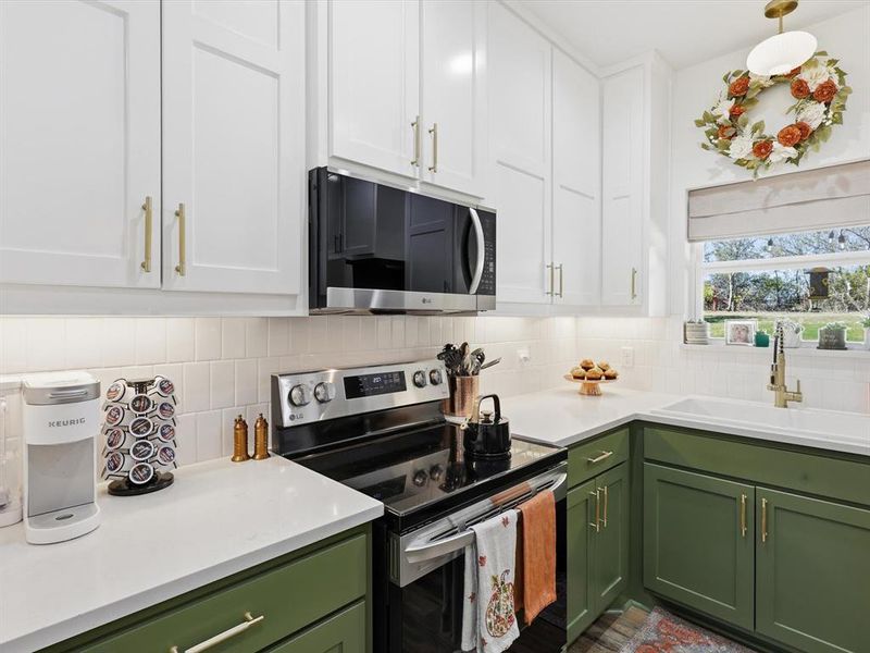 Kitchen featuring green cabinetry, appliances with stainless steel finishes, and white cabinetry
