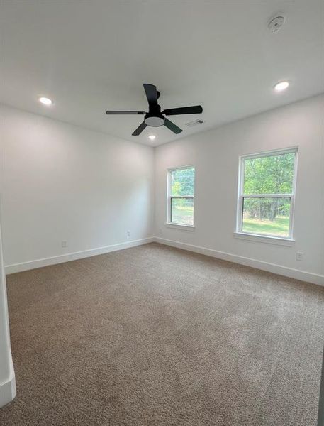 Unfurnished room with dark carpet and ceiling fan