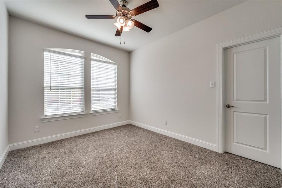 Carpeted bedroom with ceiling fan and walk-in closet.