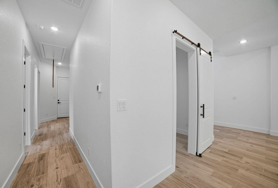 Hallway featuring recessed lighting, attic access, light wood-style flooring, and a barn door Hallway featuring recessed lighting, attic access, light wood-style flooring, and a barn door