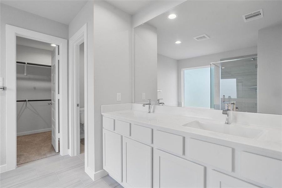 This primary bathroom is definitely move-in ready! Featuring light stained cabinets with light countertops, spacious walk-in closet with shelving, high ceilings, custom paint, sleek and dark modern finishes.