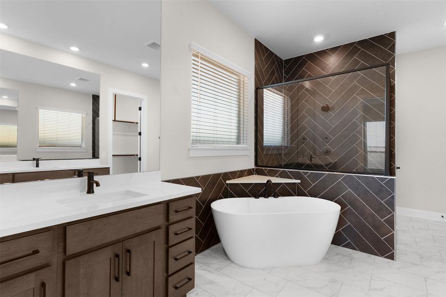 Full bathroom featuring a shower stall, tile walls, vanity, a freestanding tub, and recessed lighting
