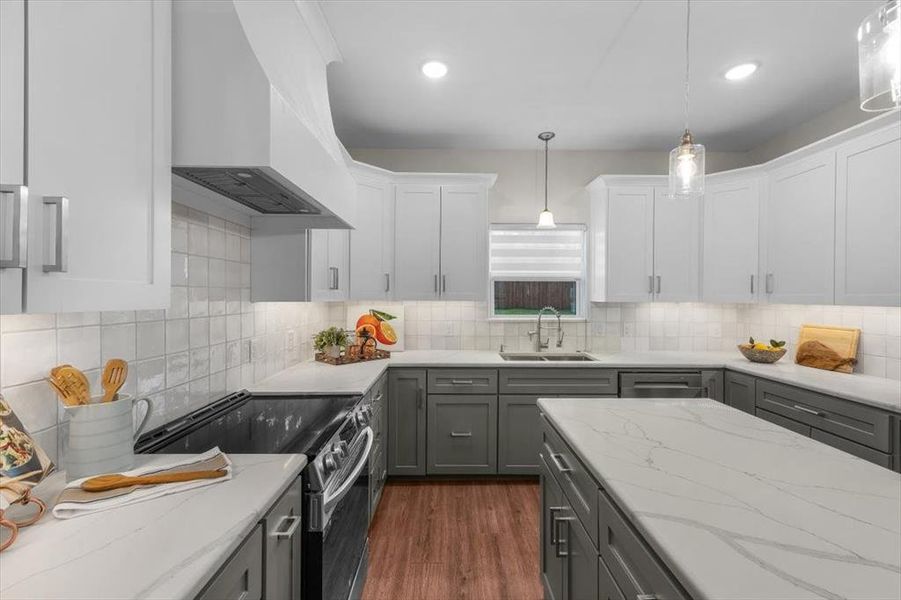 Kitchen featuring sink, gray cabinetry, decorative light fixtures, custom range hood, and electric stove