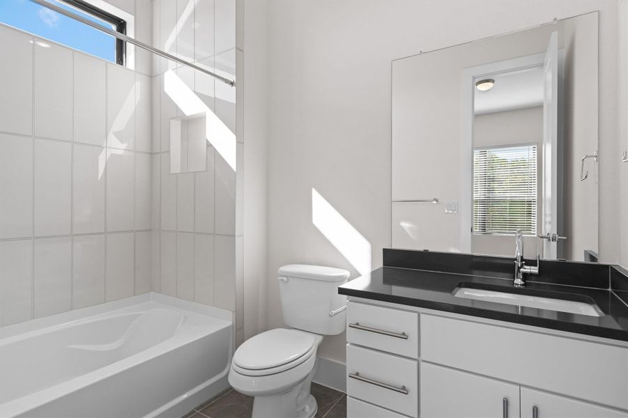 Full bathroom featuring shower / bathtub combination, dark tile patterned flooring, and vanity Full bathroom featuring shower / bathtub combination, dark tile patterned flooring, and vanity