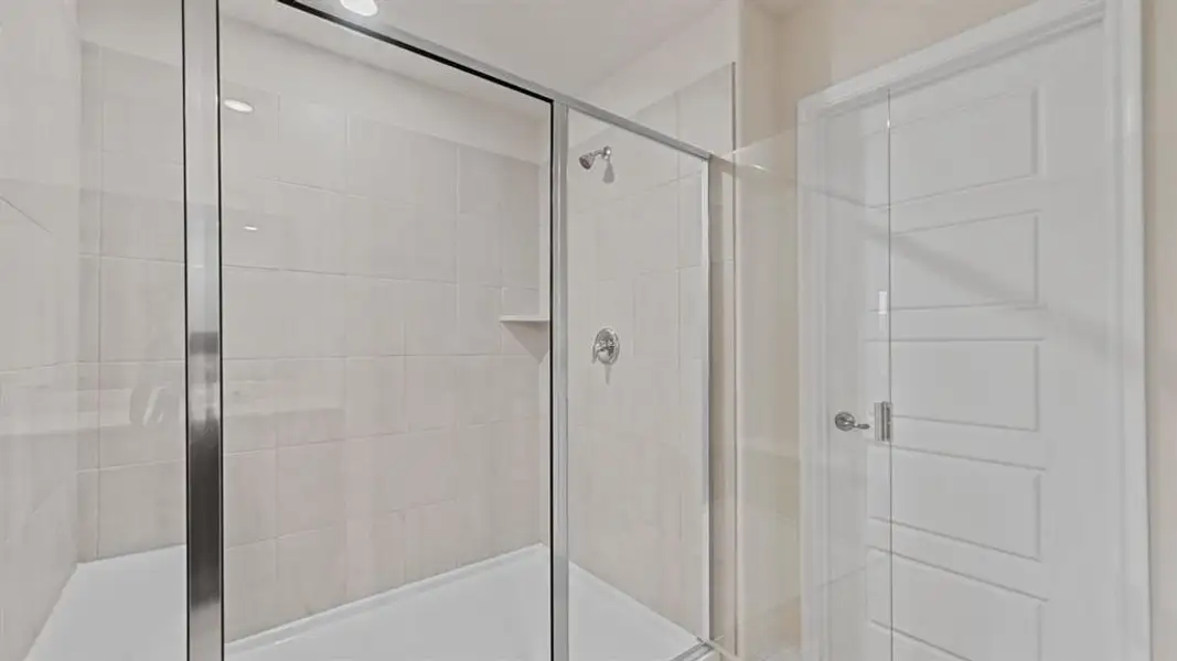 Glass-enclosed shower with subway tile surround, built-in shelving, and a chrome showerhead Glass-enclosed shower with subway tile surround, built-in shelving, and a chrome showerhead
