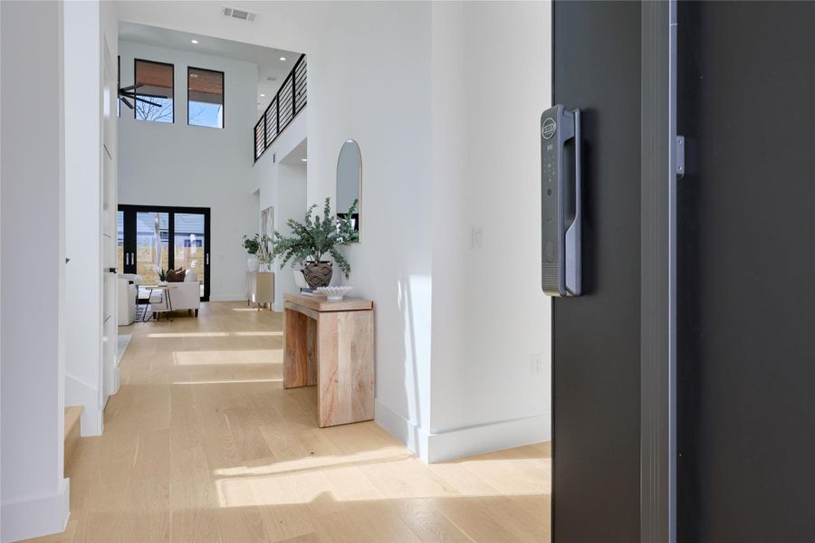 Corridor with a high ceiling, light wood-style flooring, and recessed lighting