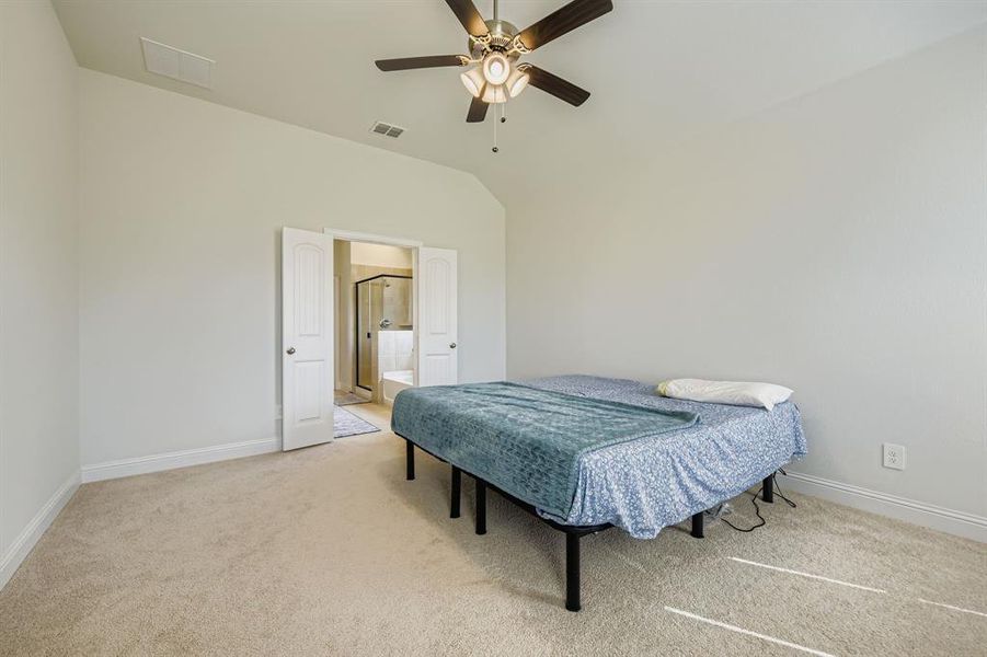 Primary bedroom with light carpet, a ceiling fan, vaulted ceiling, and ensuite bathroom Primary bedroom with light carpet, a ceiling fan, vaulted ceiling, and ensuite bathroom