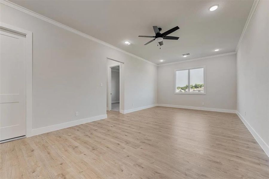 Empty room featuring ceiling fan, ornamental molding, light wood finished floors, and recessed lighting