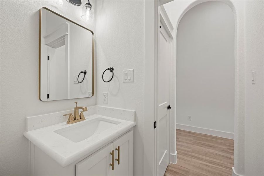 Half bathroom featuring vanity, light wood-type flooring, and a textured wall