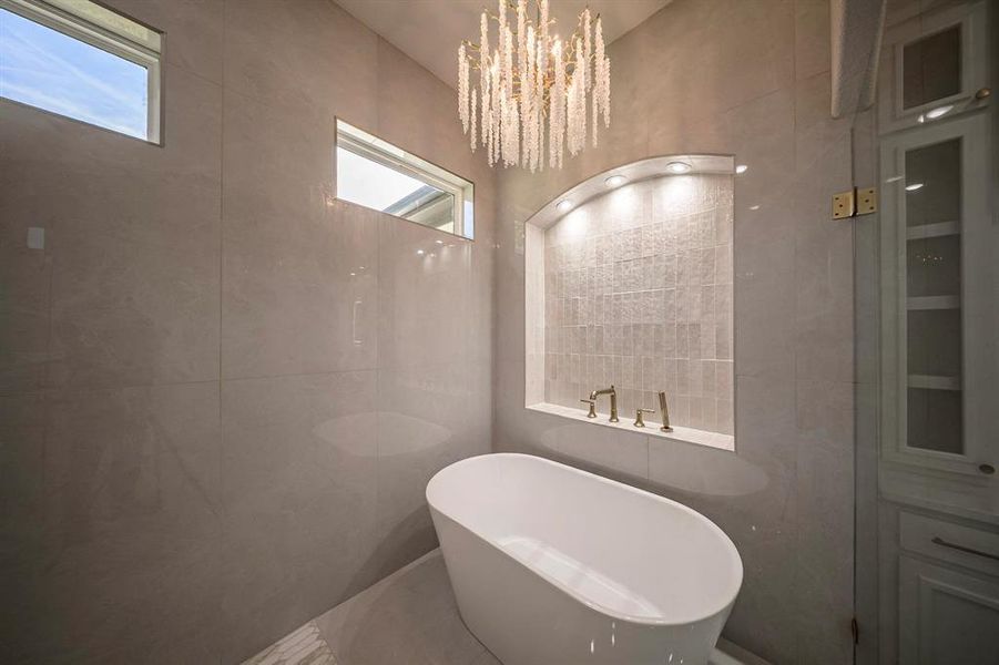 Bathroom featuring a freestanding bath, tile walls, and a chandelier Bathroom featuring a freestanding bath, tile walls, and a chandelier