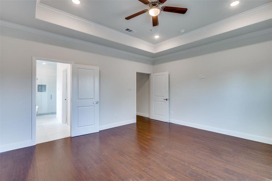 Tiled spare room featuring crown molding, ceiling fan, and a raised ceiling