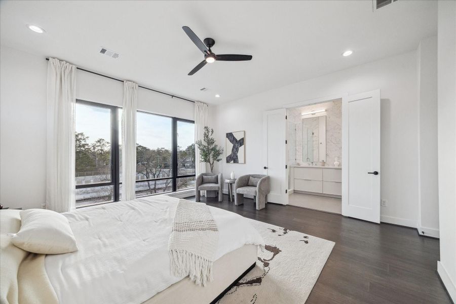 Private third-floor primary suite retreat featuring large picture windows, wide-plank flooring, and abundant natural light. Spa-inspired bath includes dual sinks, quartz countertops, soaking tub, glass-enclosed shower, and an expansive walk-in closet. Designed for comfort and tranquility, this luxurious owner’s suite offers refined finishes and contemporary elegance.