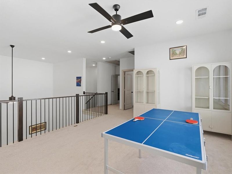 Spacious loft area featuring light-colored carpeting and bright white walls