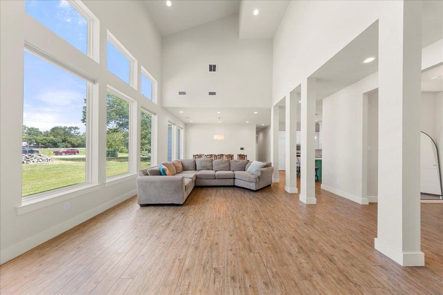 Living room with light wood-style floors, recessed lighting, and a high ceiling Living room with light wood-style floors, recessed lighting, and a high ceiling
