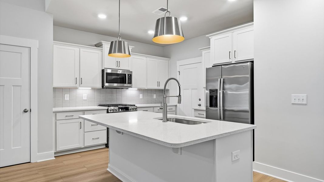 Memorable meals begin in this vibrant kitchen with pendant lighting and a thoughtfully designed island