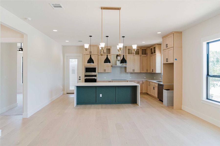 Kitchen with a kitchen island with sink, healthy amount of natural light, glass insert cabinets, stainless steel appliances, and recessed lighting