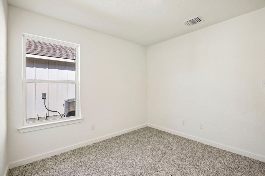 Soft carpeting pairs with crisp walls and a large window in this neutral space.