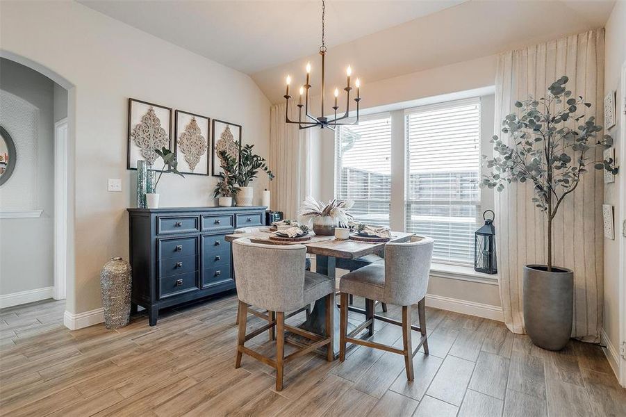 Dining room featuring vaulted ceiling, light hardwood / wood-style flooring, and a notable chandelier