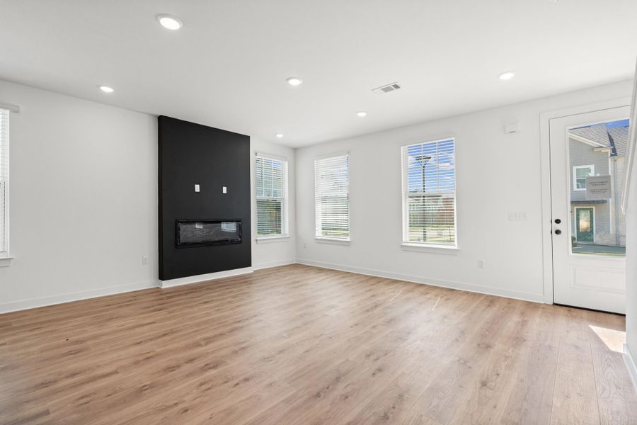 Wood-finish flooring, recessed lighting, and an electric fireplace with a black accent wall