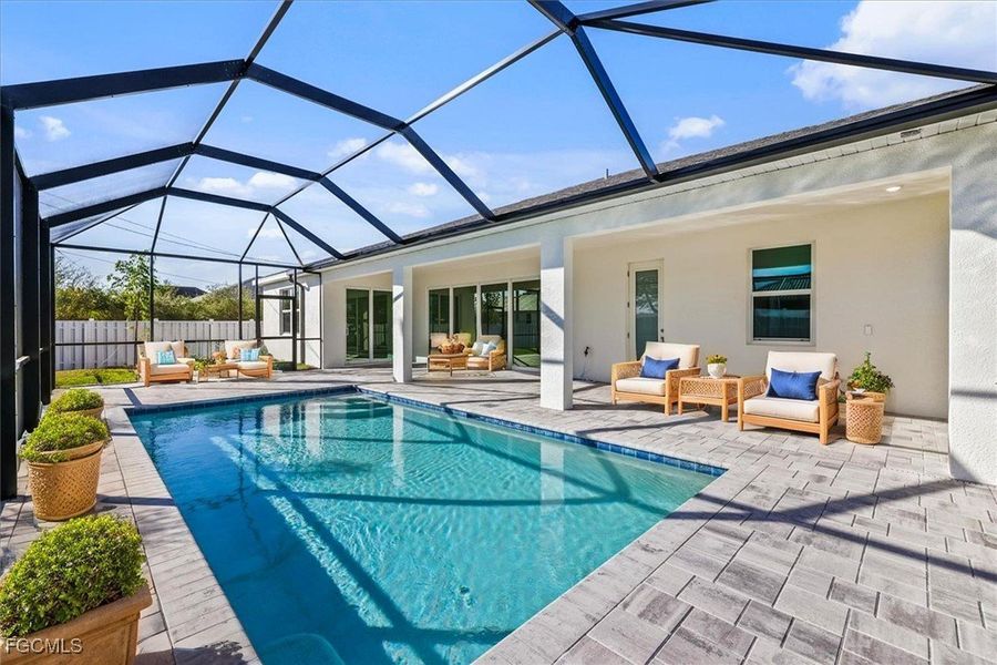 View of pool featuring an outdoor hangout area, a sunroom, a patio area, and glass enclosure