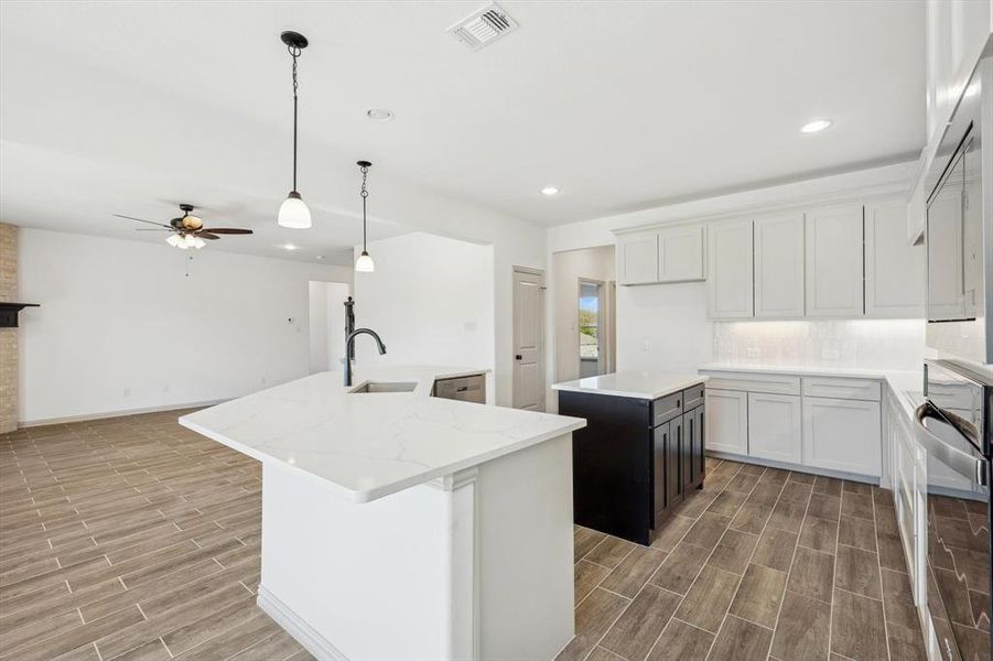 Kitchen featuring white cabinets, sink, light hardwood / wood-style flooring, and an island with sink