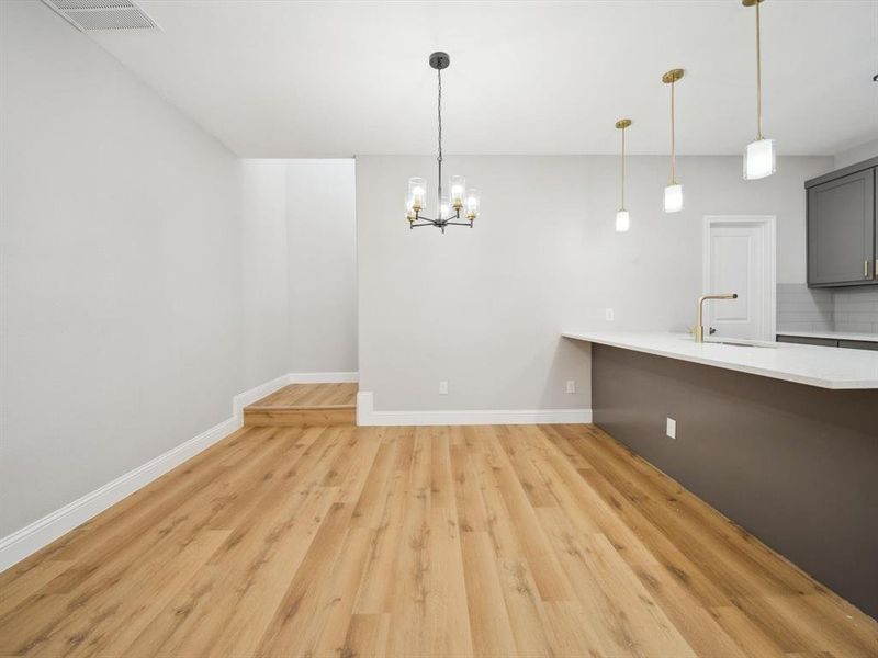 Unfurnished dining area with sink, a notable chandelier, and light hardwood / wood-style flooring