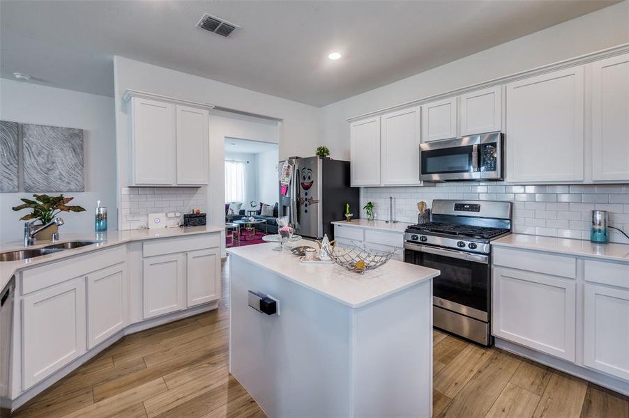 Kitchen featuring sink, white cabinetry, stainless steel appliances, and light hardwood / wood-style flooring