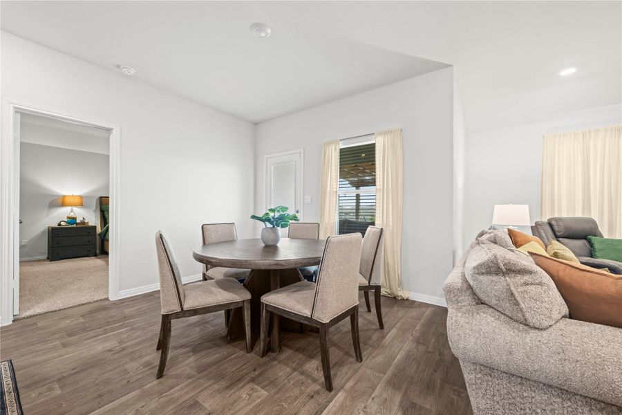 Hardwood-style flooring extends through this open-concept dining area, complemented by recessed lighting and natural illumination from the window.
