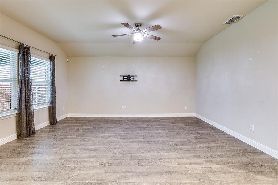 Empty room with lofted ceiling, light wood-type flooring, and ceiling fan Empty room with lofted ceiling, light wood-type flooring, and ceiling fan