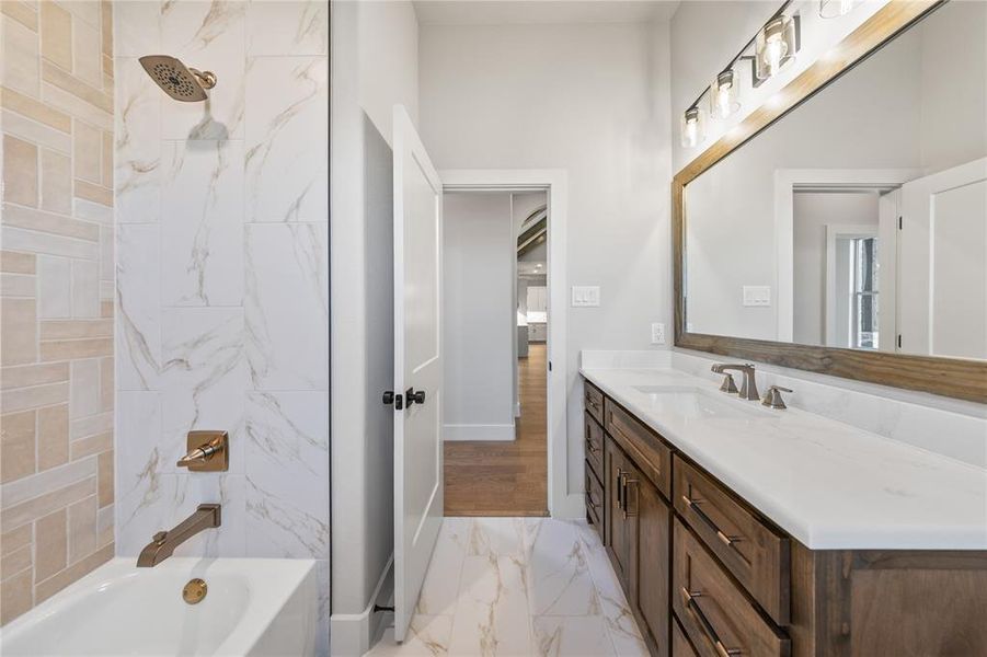 Full bath with vanity, shower / bath combination, and light marble finish floors