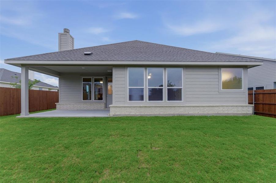 Expansive green lawn bordering a covered patio area with a concrete slab