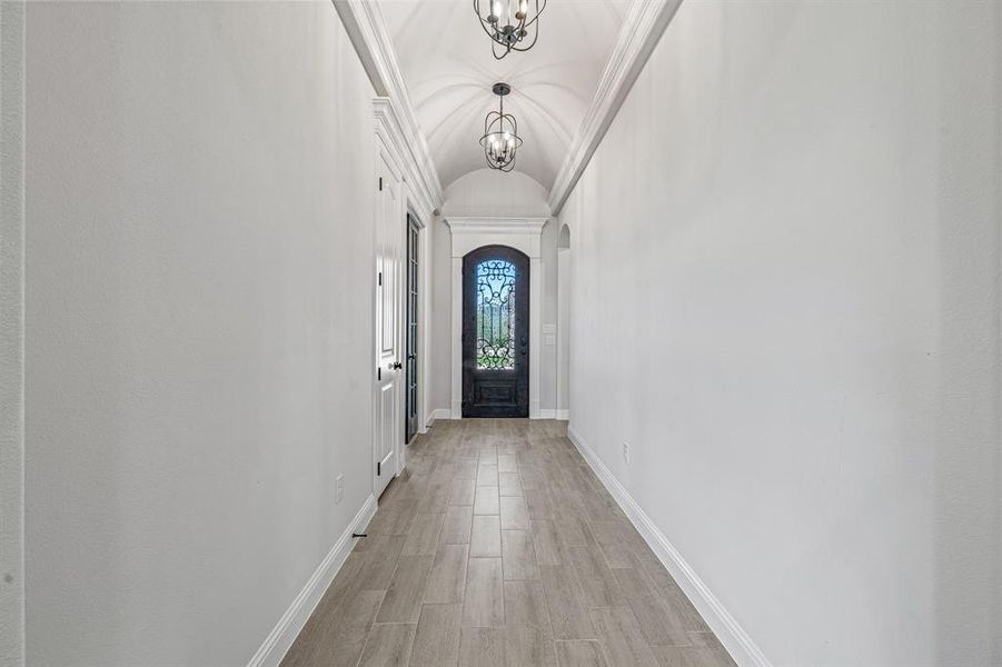 Doorway with vaulted ceiling, wood tiled floors, a chandelier, and arched walkways