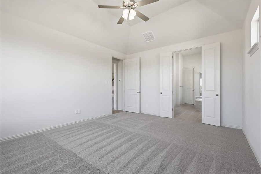 Carpeted room with a vaulted ceiling and ceiling fan