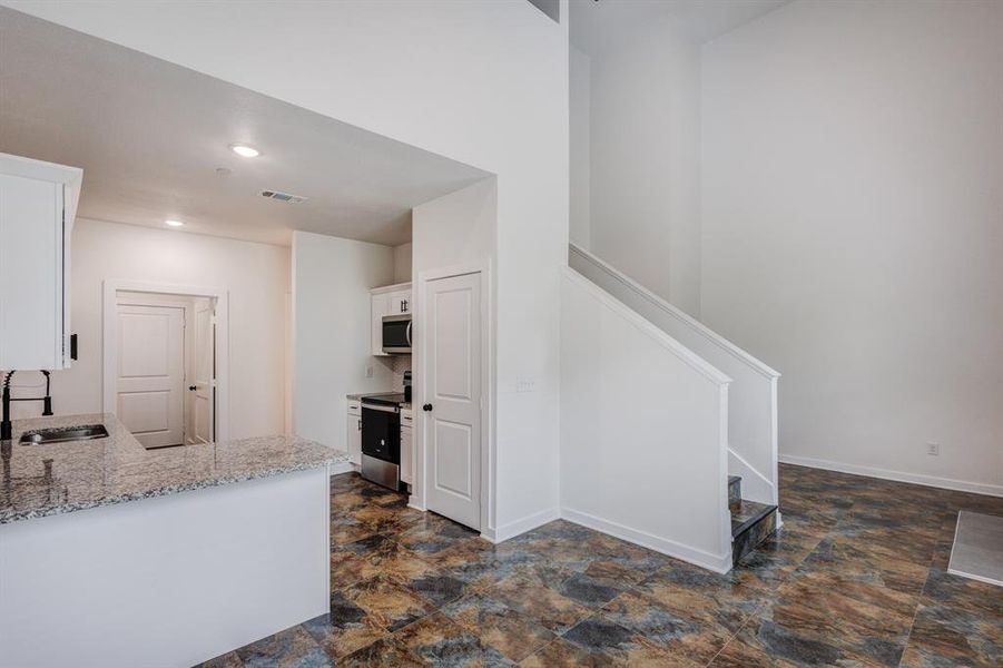 Kitchen with sink, electric range oven, white cabinets, and dark tile patterned floors