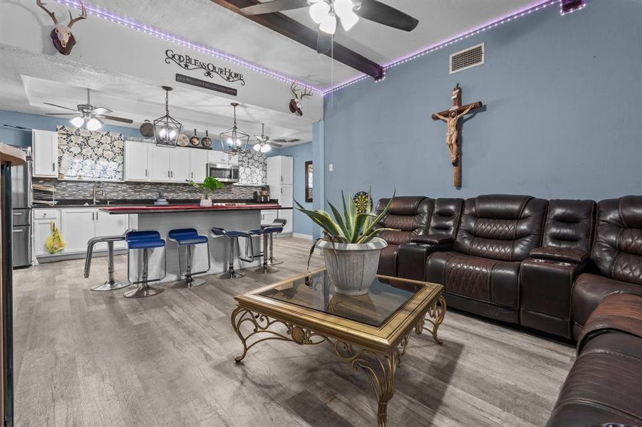 Living room featuring beam ceiling, sink, and light hardwood / wood-style flooring