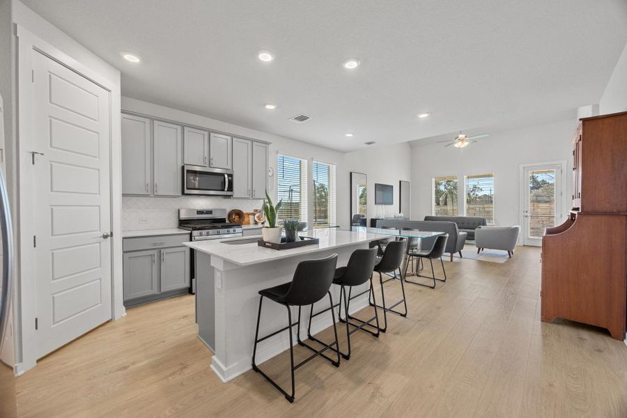 Kitchen with stainless steel appliances, a breakfast bar, large corner pantry, and an open floor plan.