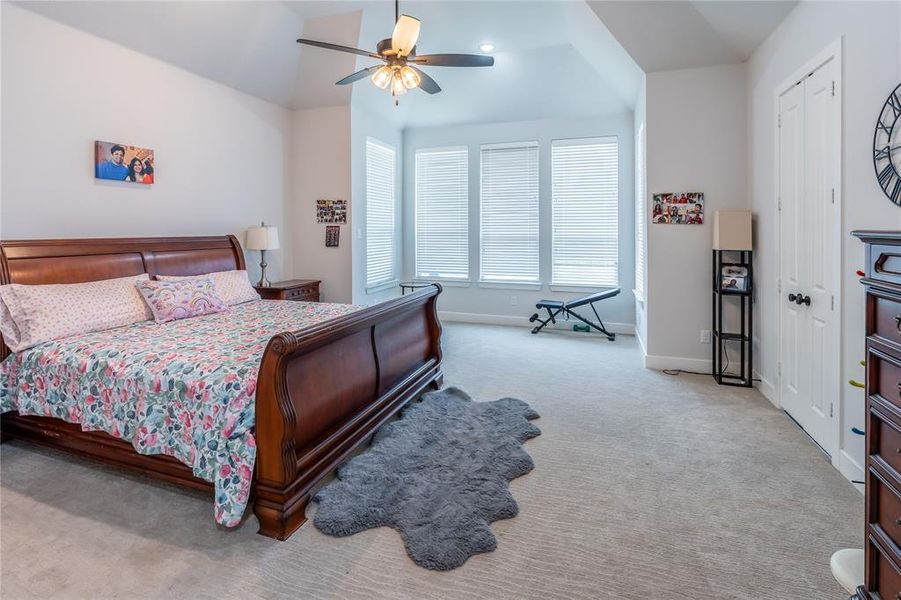 Bedroom with light carpet, a ceiling fan, and lofted ceiling