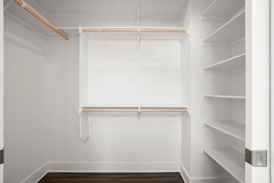 An organized walk-in closet with ample shelving and hanging space. An organized walk-in closet with ample shelving and hanging space.