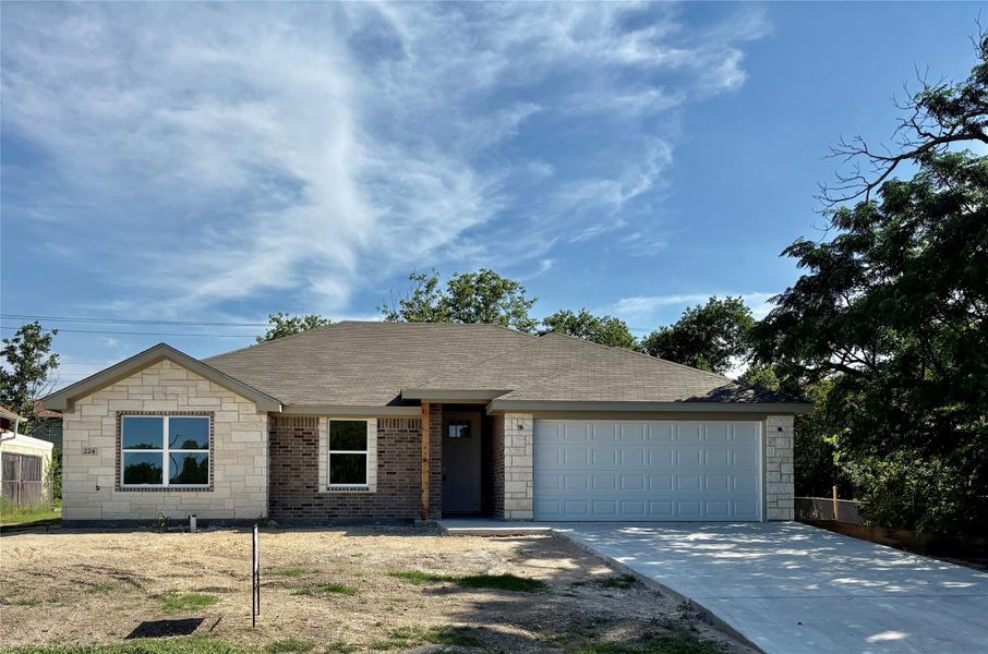 Ranch-style house featuring a garage, driveway, stone siding, and a shingled roof