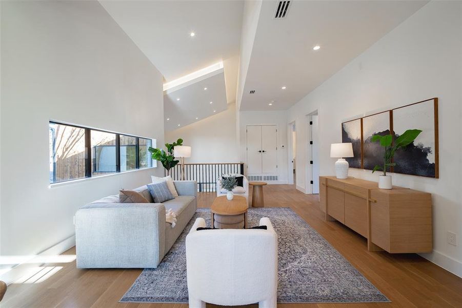 Living room with a towering ceiling and light wood-type flooring