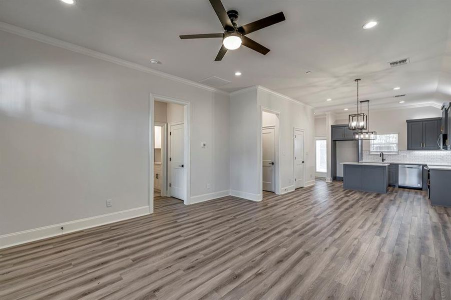 Unfurnished living room featuring recessed lighting, a chandelier, dark wood-style flooring, ornamental molding, and ceiling fan Unfurnished living room featuring recessed lighting, a chandelier, dark wood-style flooring, ornamental molding, and ceiling fan
