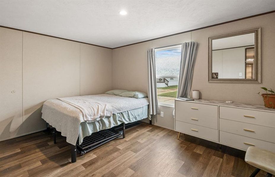 Bedroom featuring wood-finish flooring, recessed ceiling lighting, and a window with natural light Bedroom featuring wood-finish flooring, recessed ceiling lighting, and a window with natural light