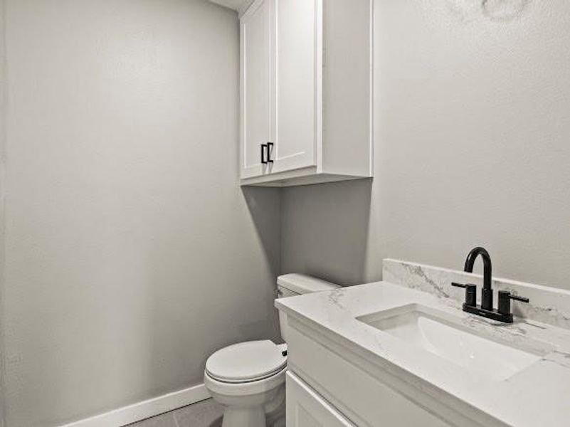Half bathroom with vanity and a textured wall