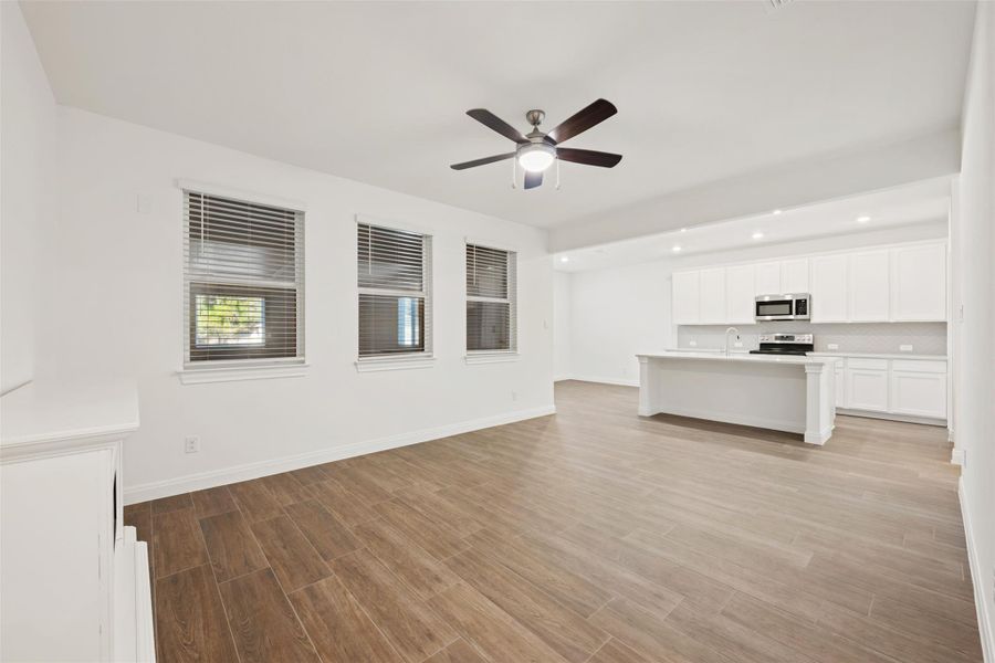 Unfurnished living room featuring light wood-type flooring, ceiling fan, and recessed lighting Unfurnished living room featuring light wood-type flooring, ceiling fan, and recessed lighting