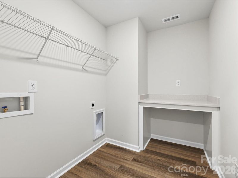 Laundry room features folding table with quartz countertop & LVP flooring