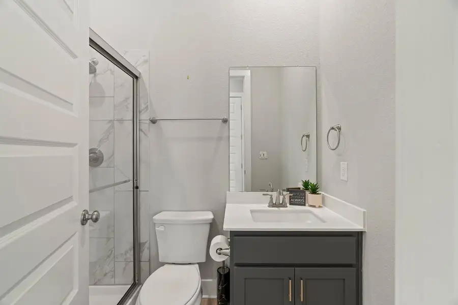 Bathroom with a textured wall, a marble finish shower, and vanity Bathroom with a textured wall, a marble finish shower, and vanity
