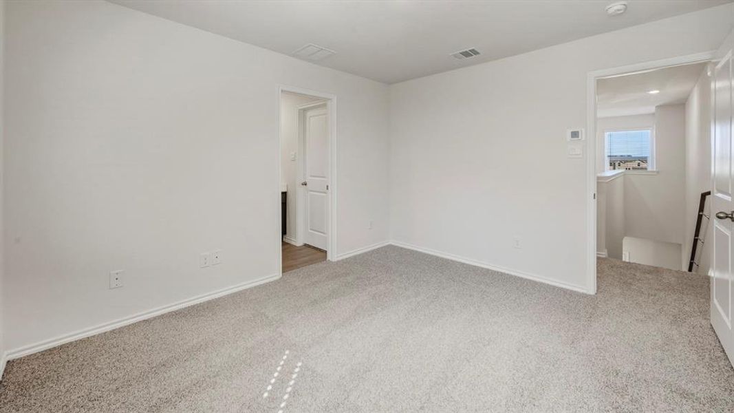Unfurnished bedroom with light colored carpet and baseboards