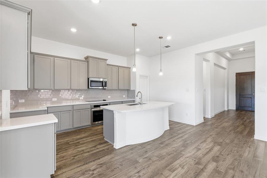 Modern kitchen featuring light gray cabinetry, subway tile backsplash, and light-toned countertops